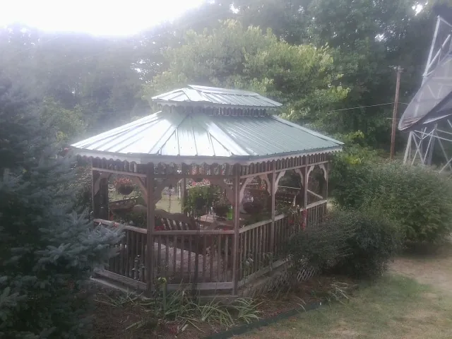 Green metal roof on a backyard gazebo surrounded by garden beds in Livingston