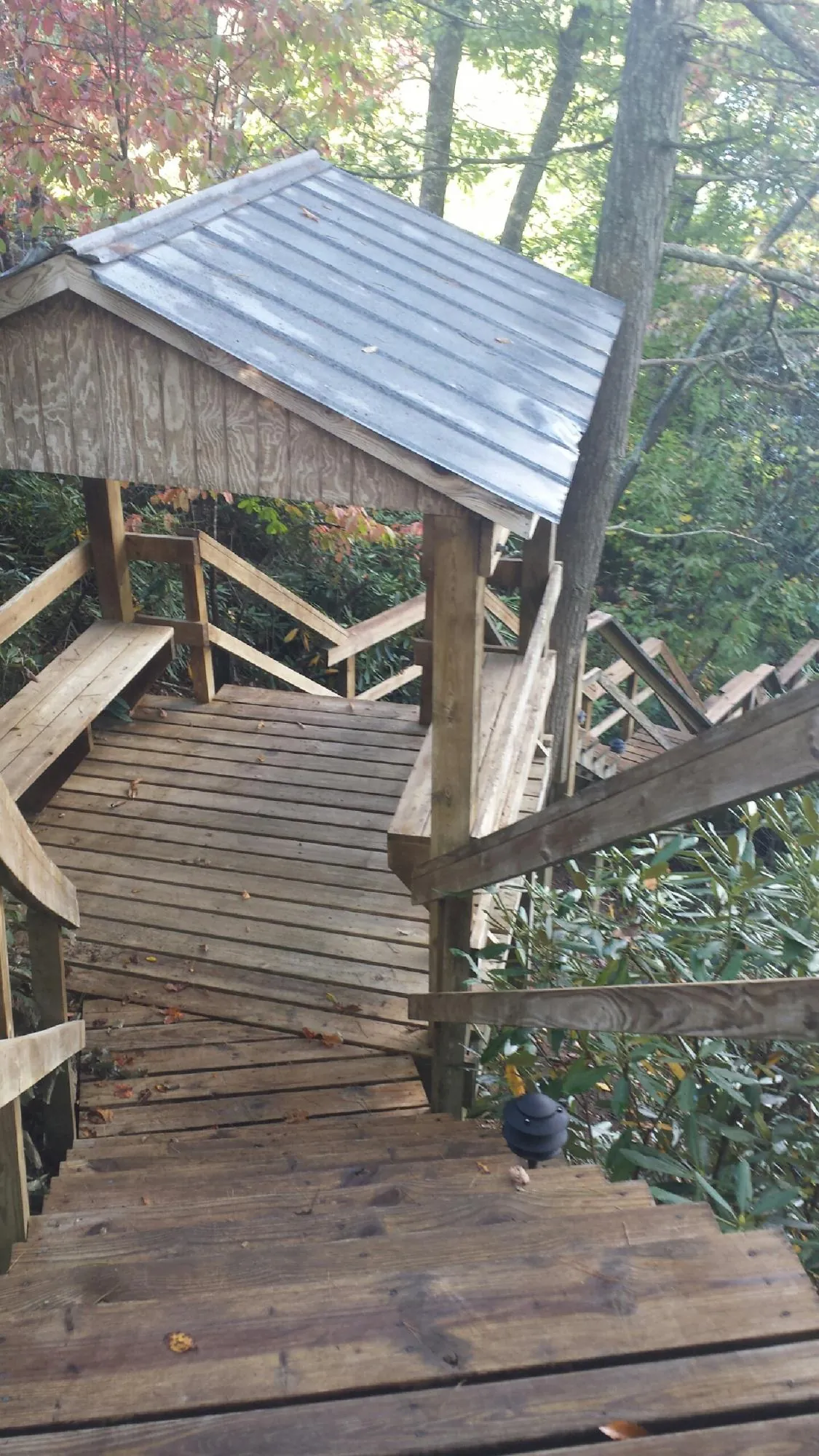 Metal roofed shelter over wooden steps on a wooded walkway — Skylight Repair & Installation work by our crew in Livingston